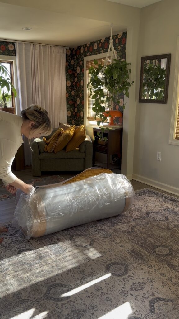 Compressed couch wrapped in plastic packaging after being removed from the box