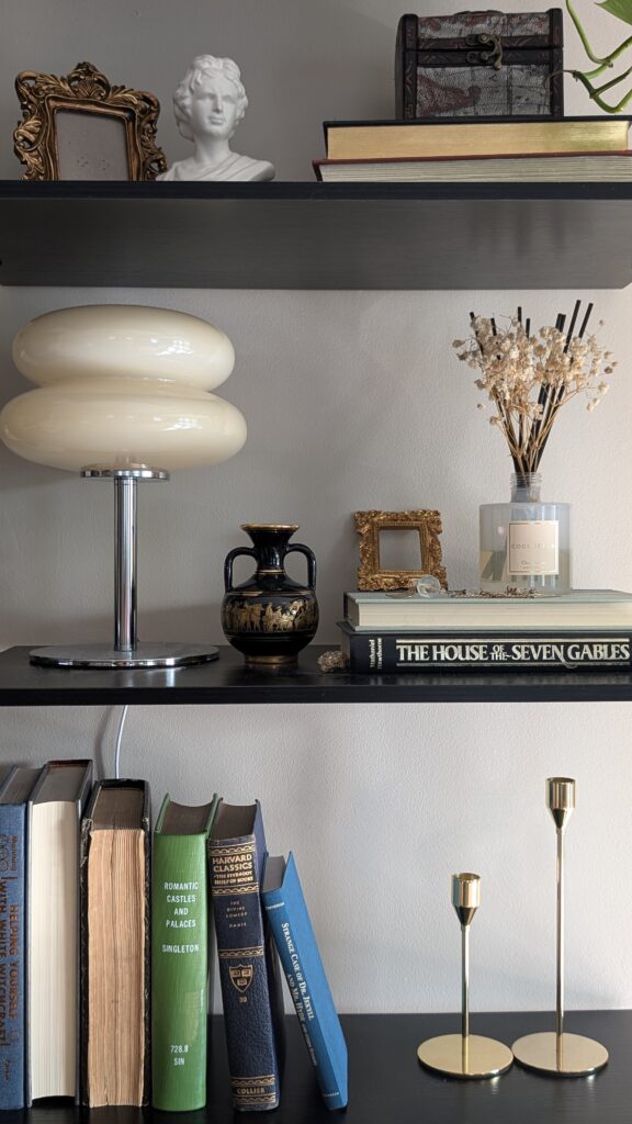 Modern globe table lamp with dimmer switch styled on a dark wood shelf with books and neutral decor.