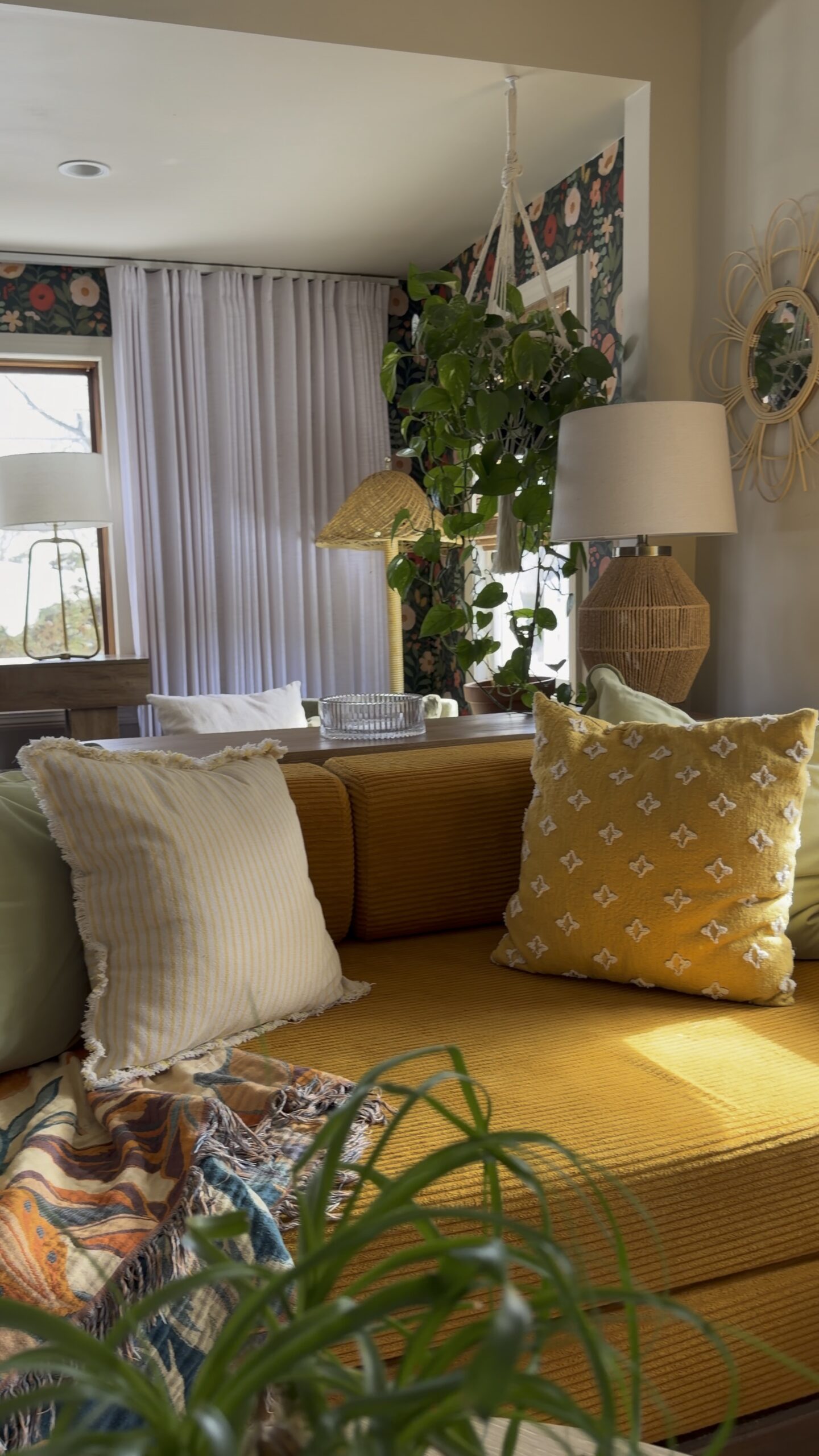 cozy living room with mustard yellow sofa, green plants and textured yellow throw pillows