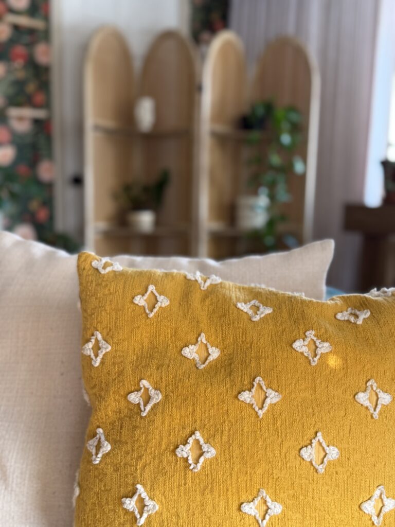 Mustard yellow textured throw pillow layered on neutral sofa in cozy living room with warm natural light.