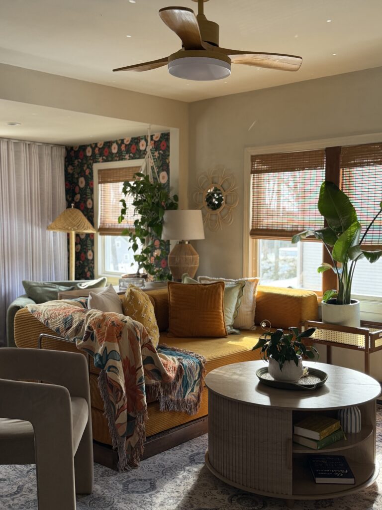 Living room with Rivers Edge by Sherwin Williams walls, bold floral wallpaper accents, mustard sofa, and layered natural textures.
