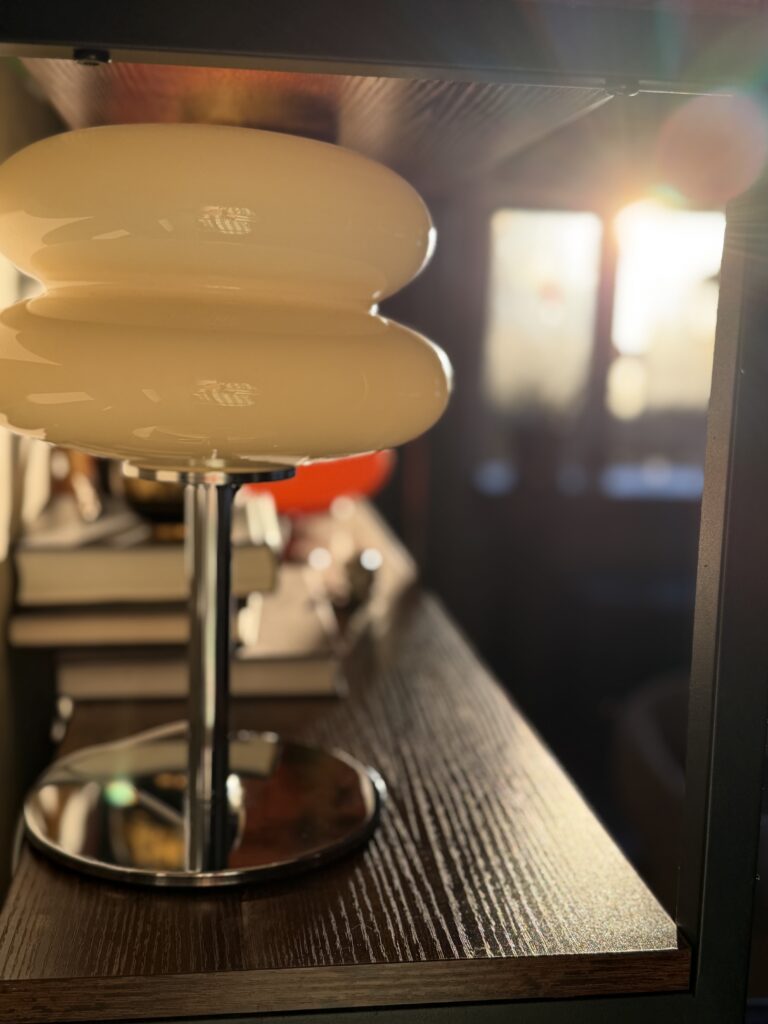warm toned glass table lamp styled on a dark wood shelf with soft natural light