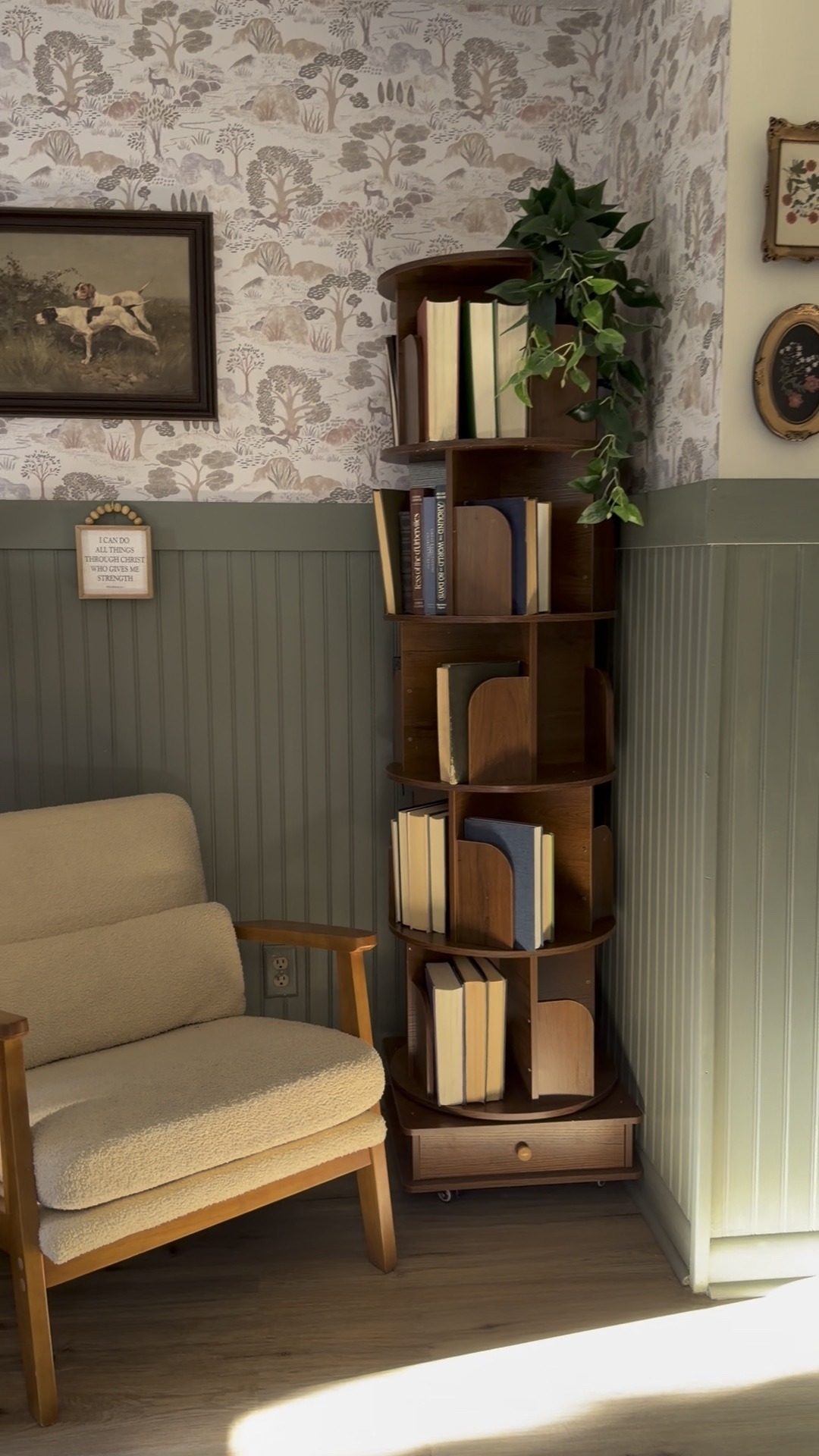 tall rotating wooden bookshelf styled with neutral books and greenery in corner
