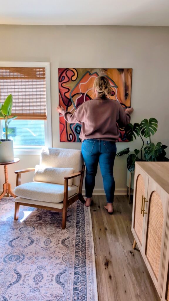 large canvas wall art installed above chair in styled living room
