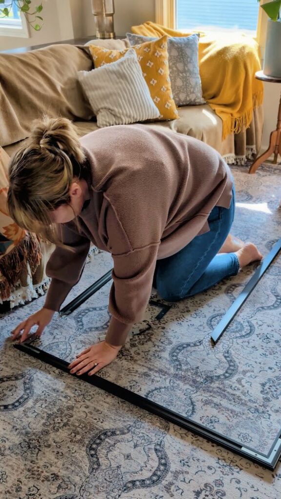 assembling big wall decor frame on rug in living room