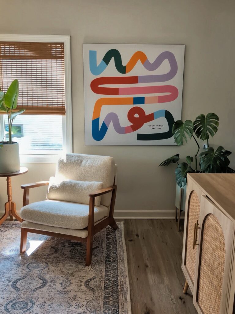 large colorful abstract wall art above accent chair with plants and natural light