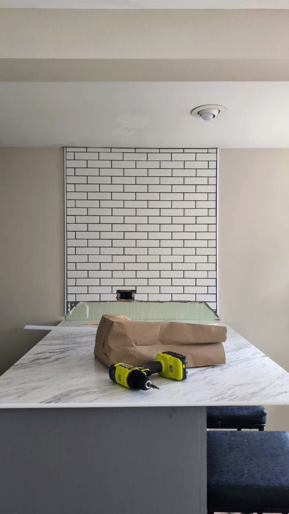 White subway tile backsplash with dark grout before grout color refresh in a budget kitchen makeover