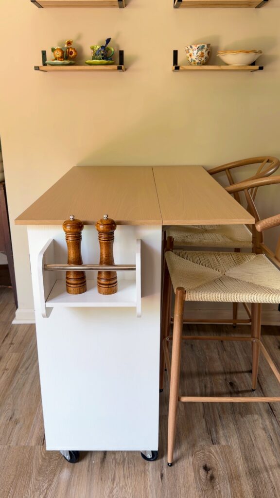 Rolling kitchen island with drop-leaf countertop extended to create seating for two in a small kitchen.