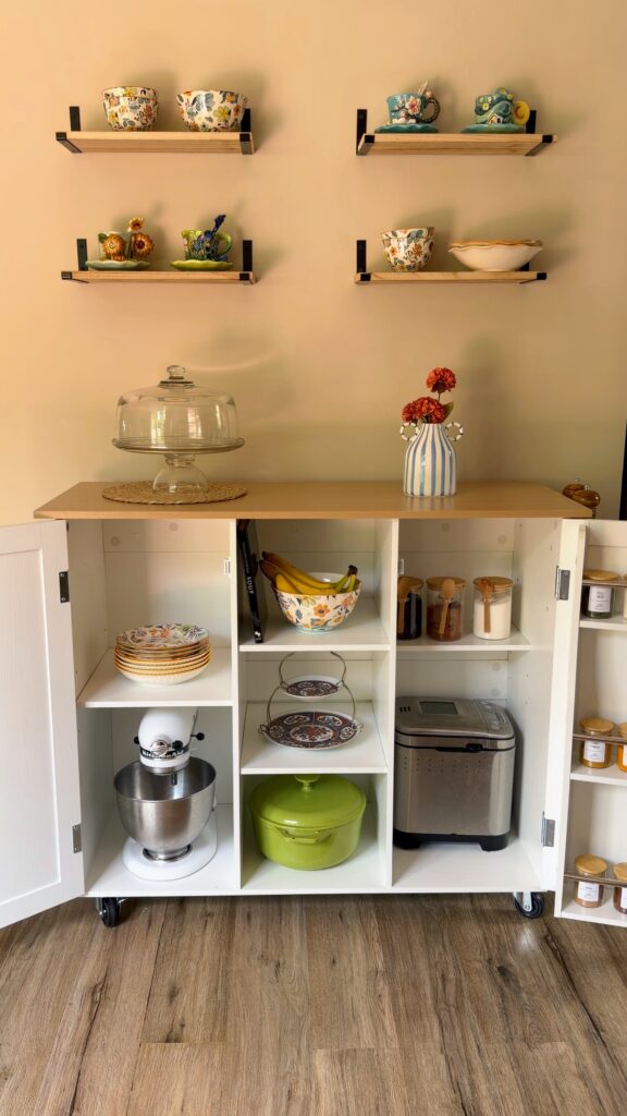 Inside storage of a rolling kitchen island showing a KitchenAid stand mixer and large kitchen appliances fitting inside the cabinet.