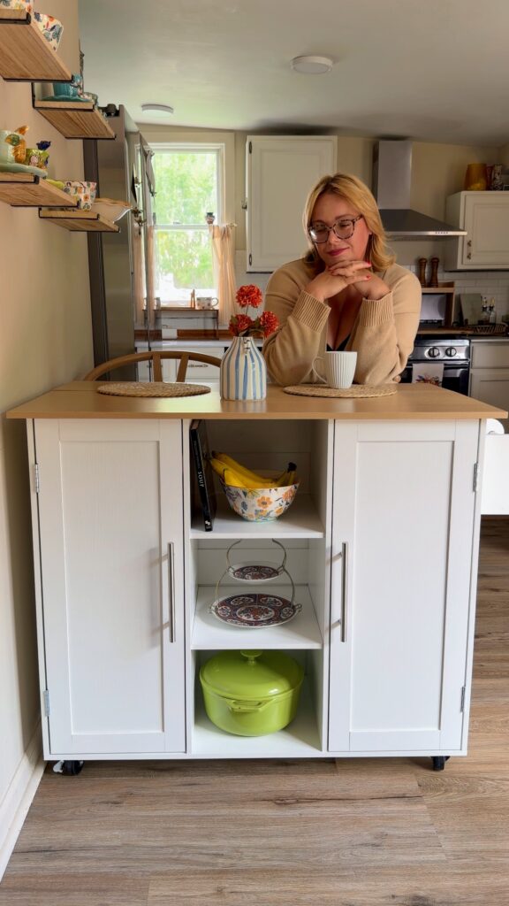 Rolling kitchen island with drop-leaf countertop extended to create seating for two in a small kitchen.