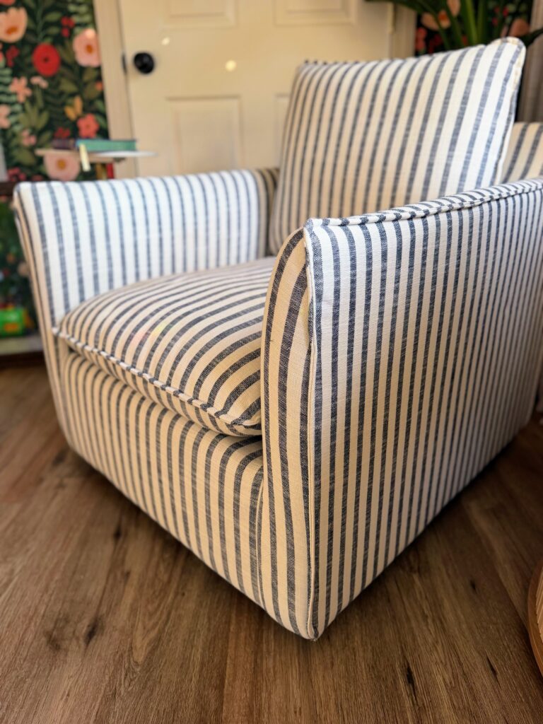 Close-up of a blue and cream ticking stripe upholstered accent chair with tailored piping.