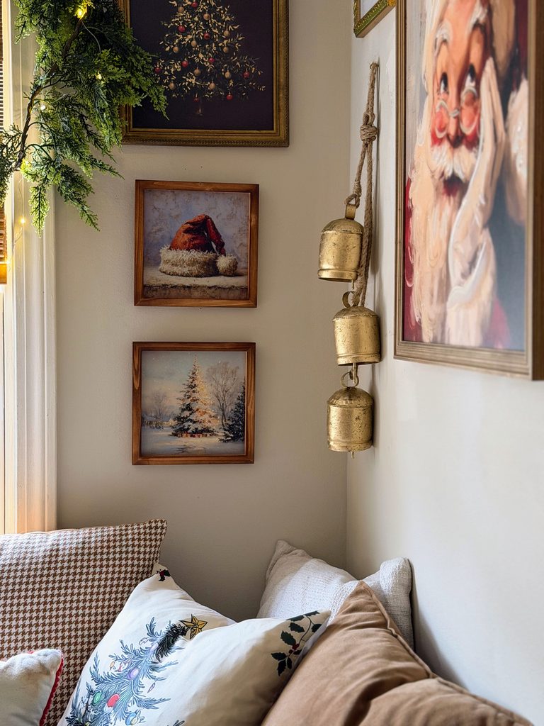 Vintage-inspired Christmas gallery wall featuring a Santa portrait, framed winter scenes, Christmas tree artwork, and hanging brass bells.